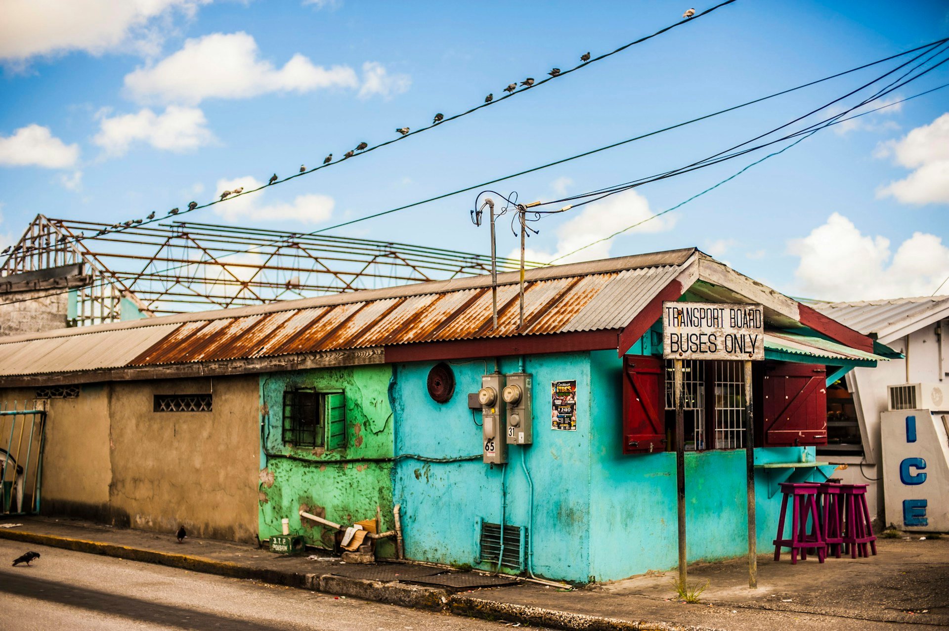 A brightly painted building with a corrugated roof under a blue sky in Barbados